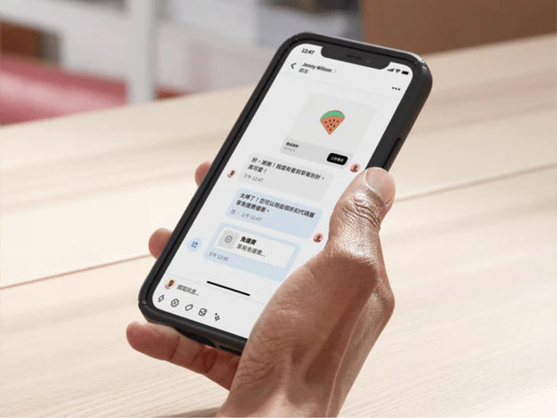 店主在後勤辦公室內用手機透過 Shopify Inbox 與顧客聊天。她在聊天時分享了一組折扣代碼，促成這筆交易。