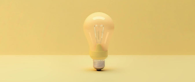 Een gele gloeilamp op een gele achtergrond die ideeën voor kunstbedrijven symboliseert.