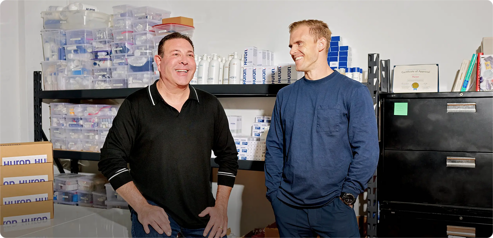 Foto der Huron-Mitbegründer, die nebeneinander stehen, mit Huron-Produkten im Hintergrund.