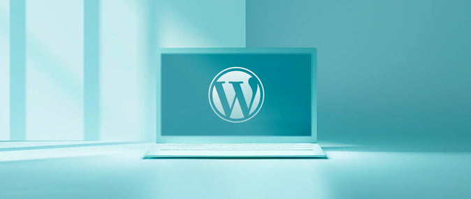Ένα ανοιχτό laptop με το λογότυπο του WordPress στην οθόνη, σε μπλε φόντο.