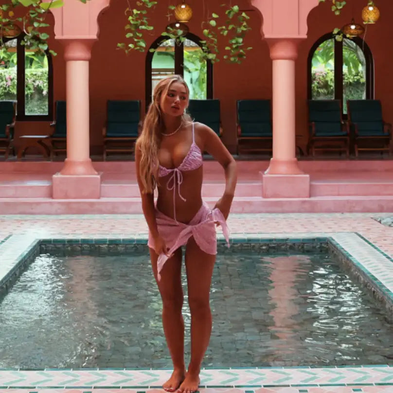 An image of a woman in pink swimwear standing at the edge of a pool.