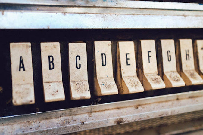 close-up van vergeelde toetsen met de letters A tot en met H op een oud toetsenbord of typemachine.