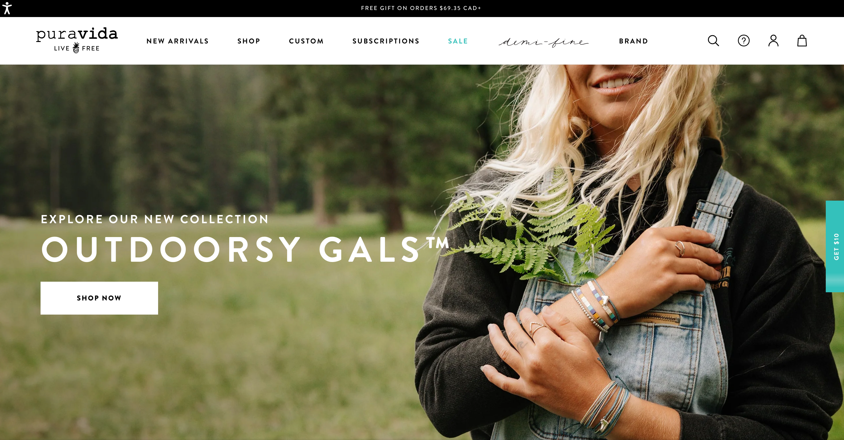 Person in overalls holding a fern with stacked bracelets and rings on the Pura Vida homepage.