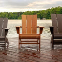 three adirondack chairs that are different sizes and different colors sitting on a wet wooden pier overlooking a body of water a beach and a treeline