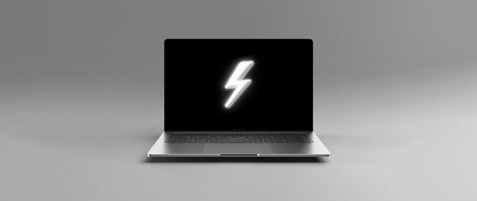 open laptop with a black screen and white lightning bolt on it in front of a grey background